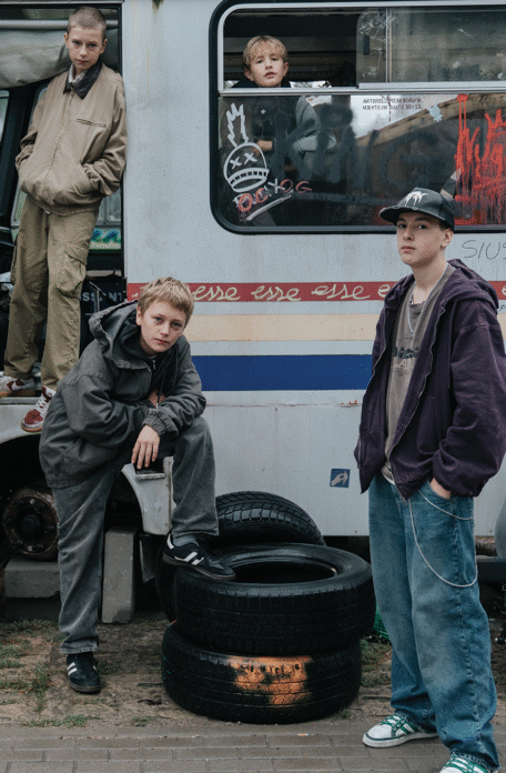 Młodzi bohaterowie pozują przy starym, zniszczonym autobusie. Kadr z filmu "Ministranci"