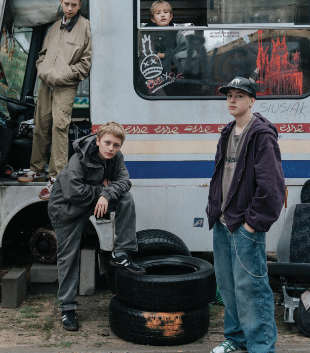 Młodzi bohaterowie pozują przy starym, zniszczonym autobusie. Kadr z filmu "Ministranci"