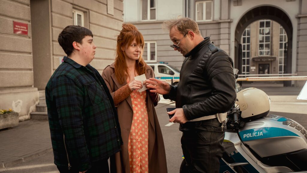 Fotos z filmu "Za duży na bajki 3". Bohaterowie - Waldi (Maciej Karaś), Tereska (Karolina Gruszka) i policjant (Borys Szyc) rozmawiają.